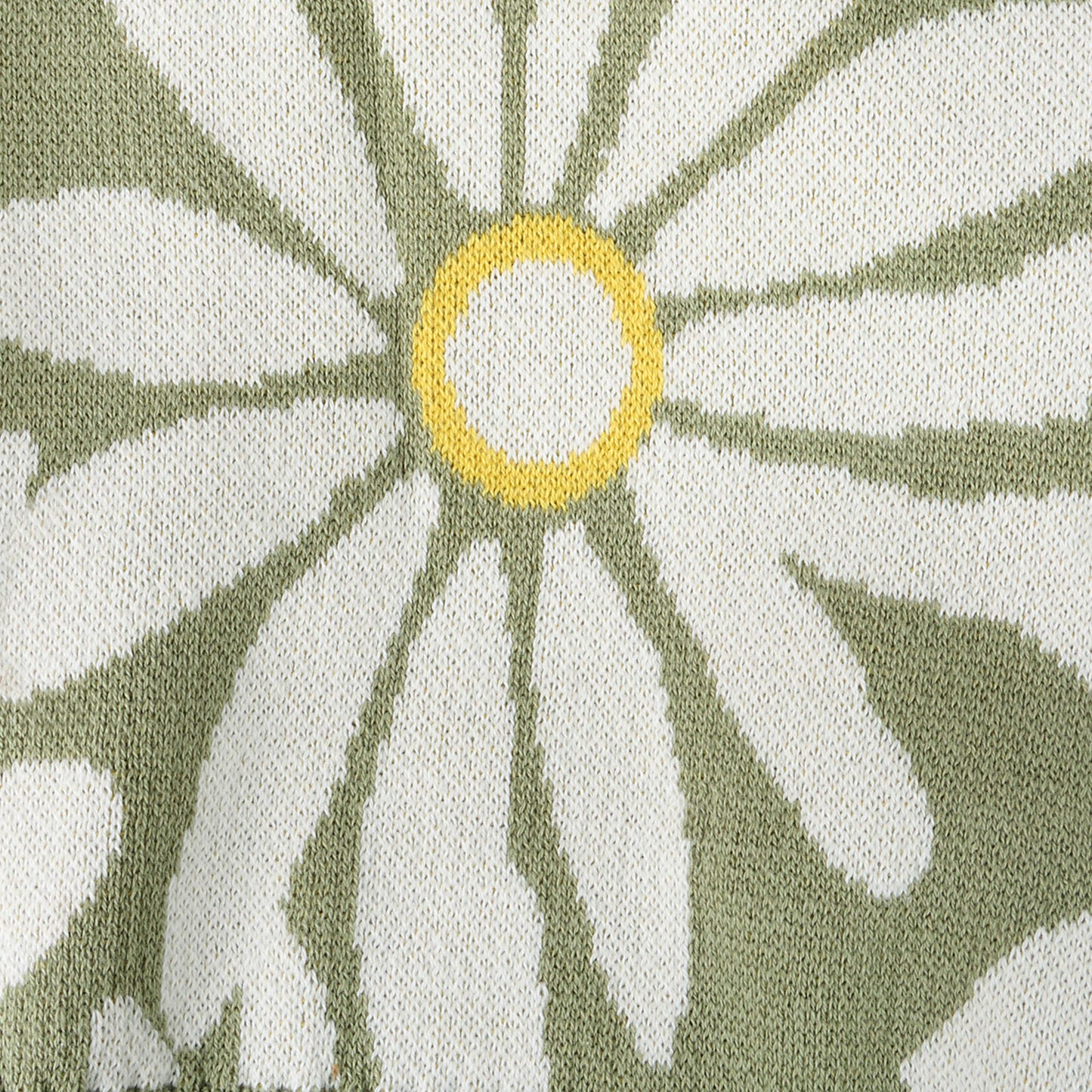 Close-up of a fabric with a floral pattern featuring green and white leaves and a yellow center.
