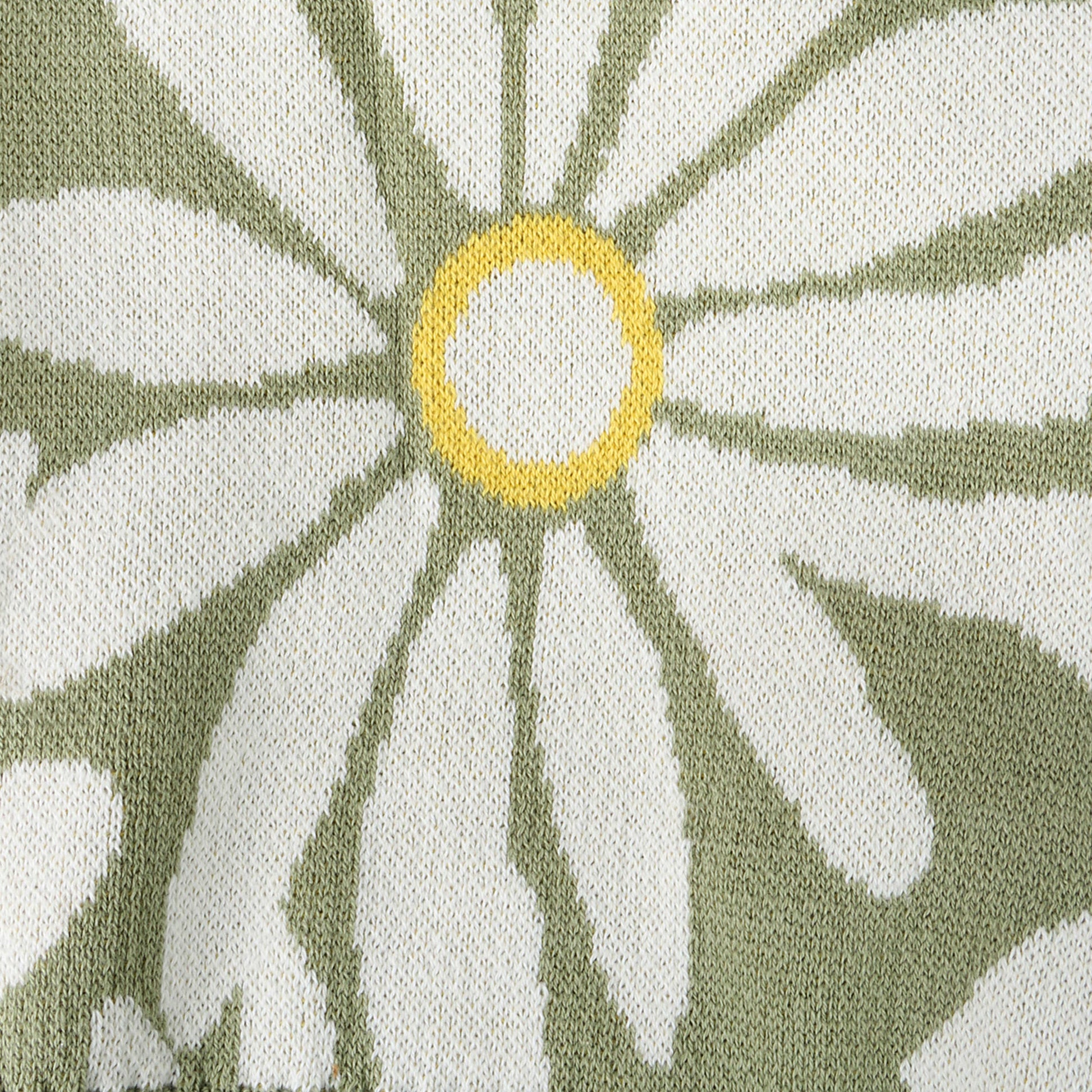 Close-up of a fabric with a floral pattern featuring green and white leaves and a yellow center.