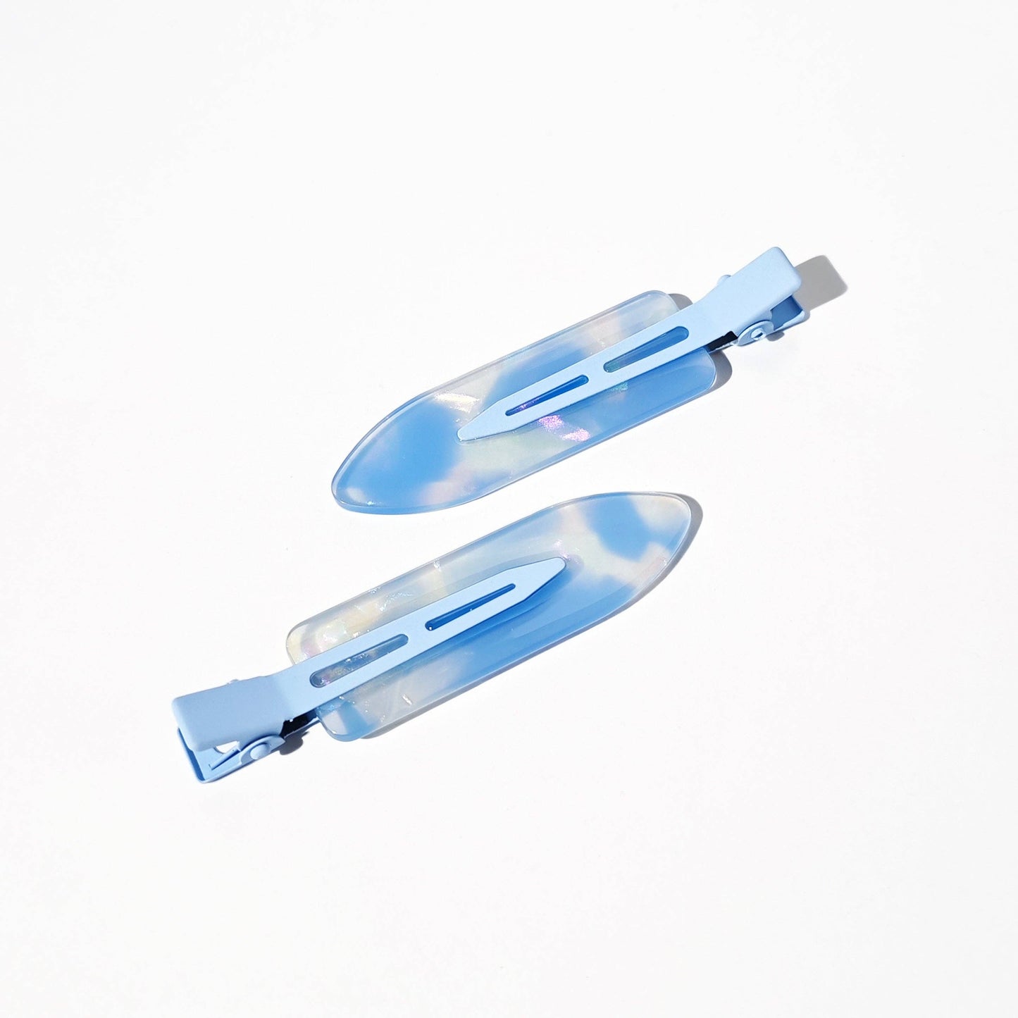 Two blue hair clips with a tie-dye pattern on a white background