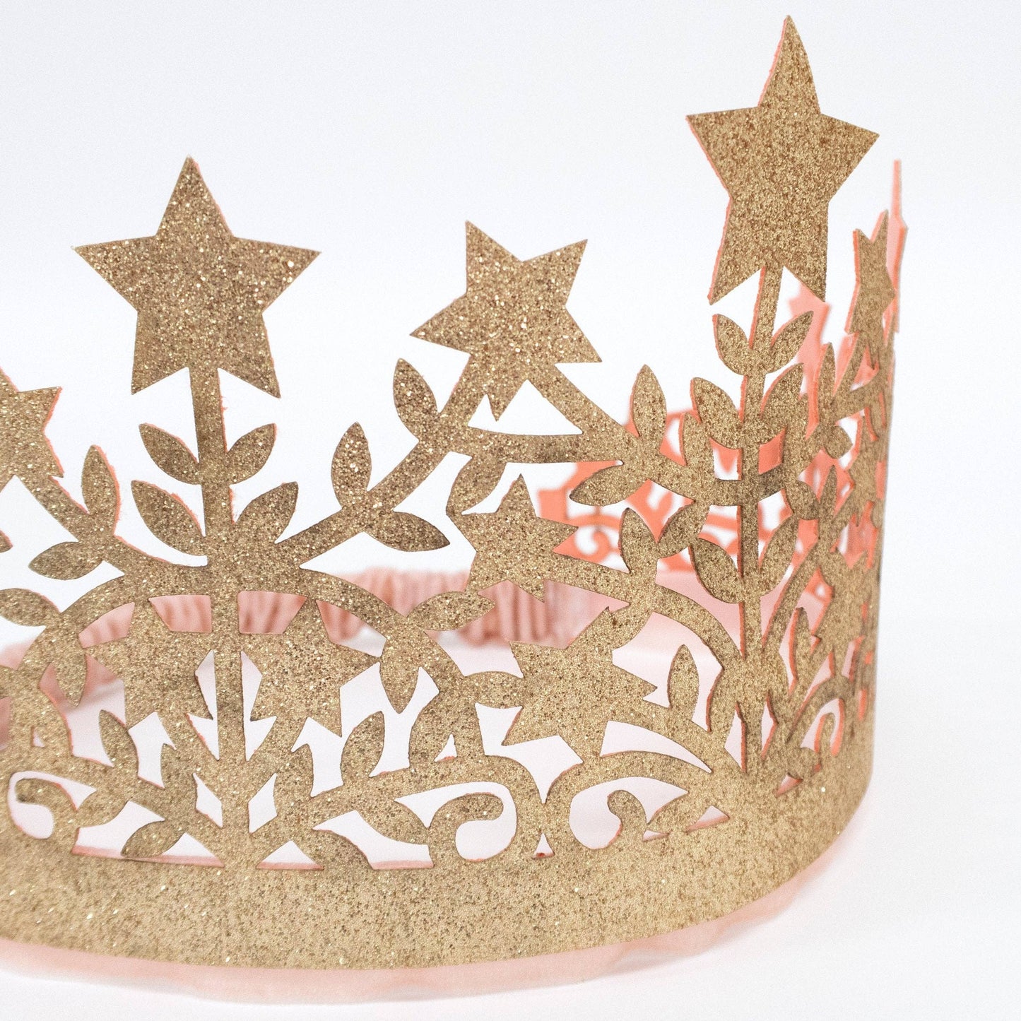 Gold glittery tiara with star designs on a white background