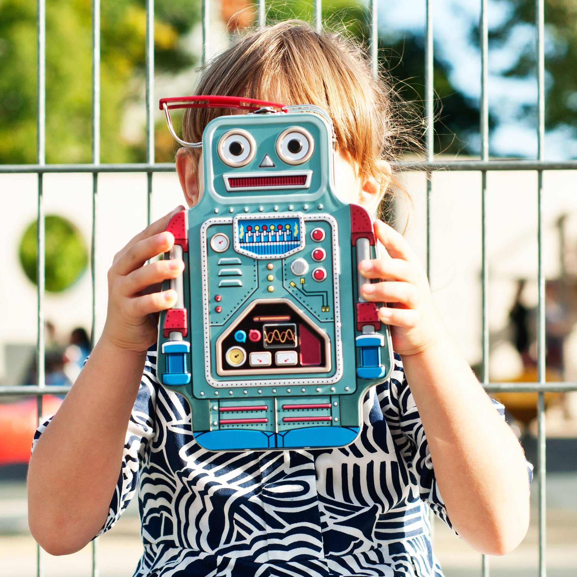 child holding a robot lunchbox in front of their face