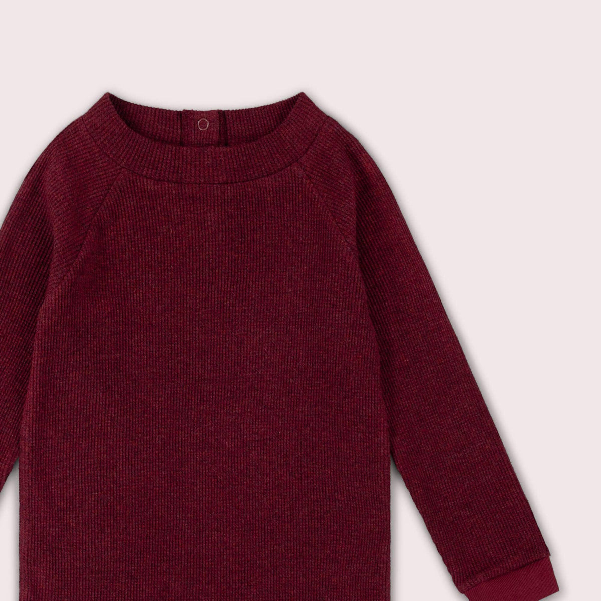 Close-up of the neckline, shoulder and waffle texture on a burgundy long-sleeve top.