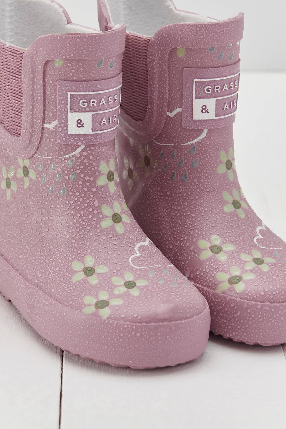 close up of pink rainboots with floral pattern with dew from raindrops on them