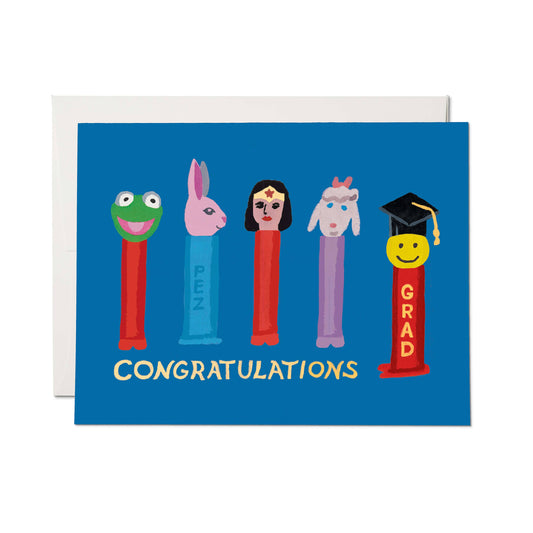 Graduation-themed PEZ candy dispenser card with colorful characters on a blue background