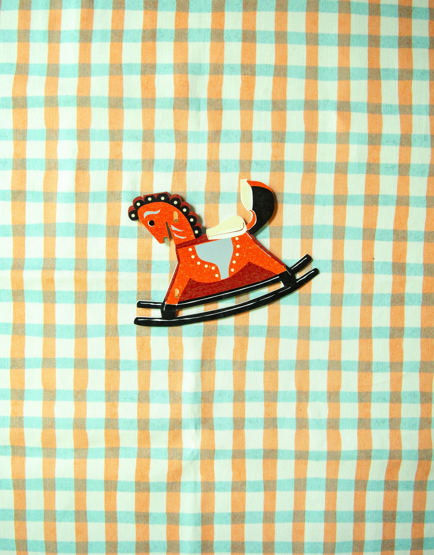 Rustic wooden rocking horse toy on a checkered fabric background