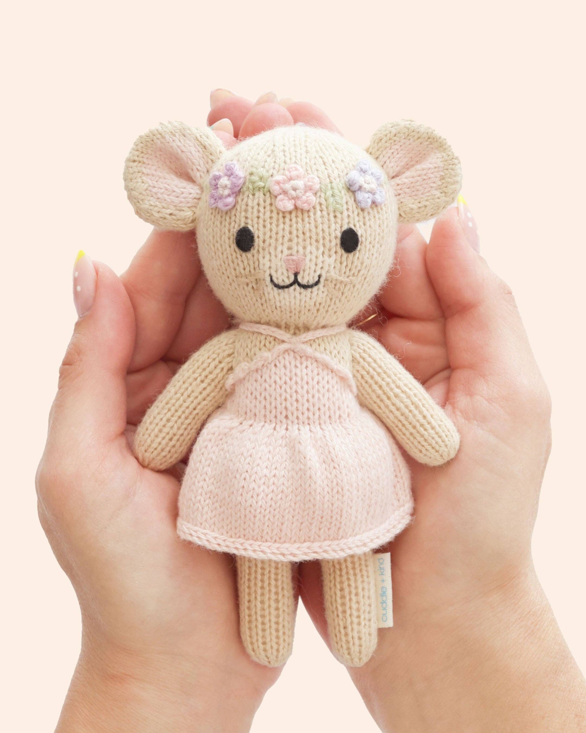 Knitted mouse toy held in hands against a light background