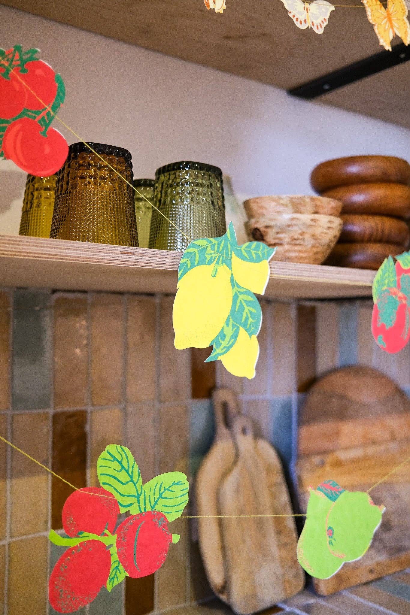 Shelf with jars, a bowl, and wooden items with decorative paper fruit and leaves.