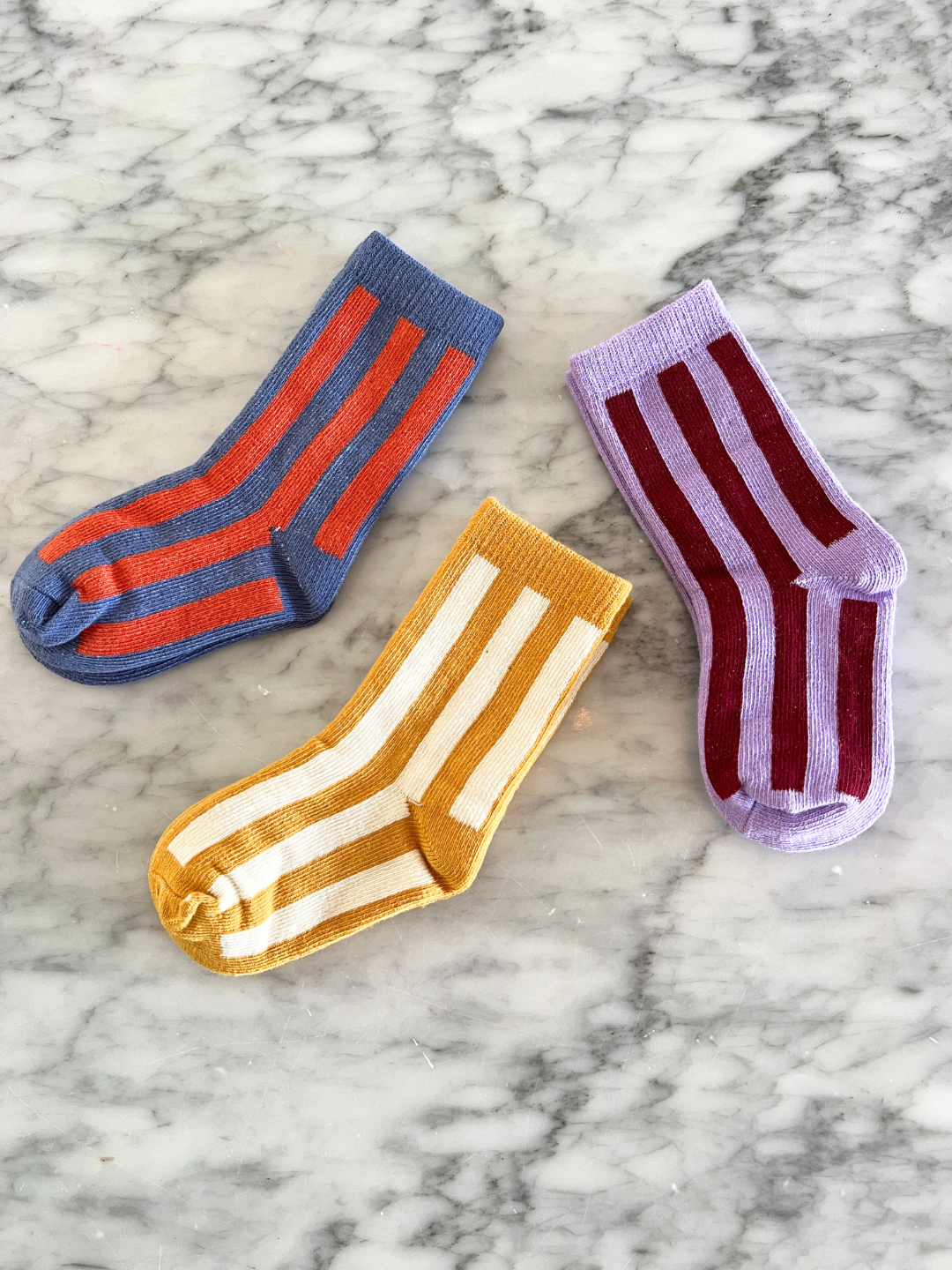 Three pairs of striped socks on a marble surface