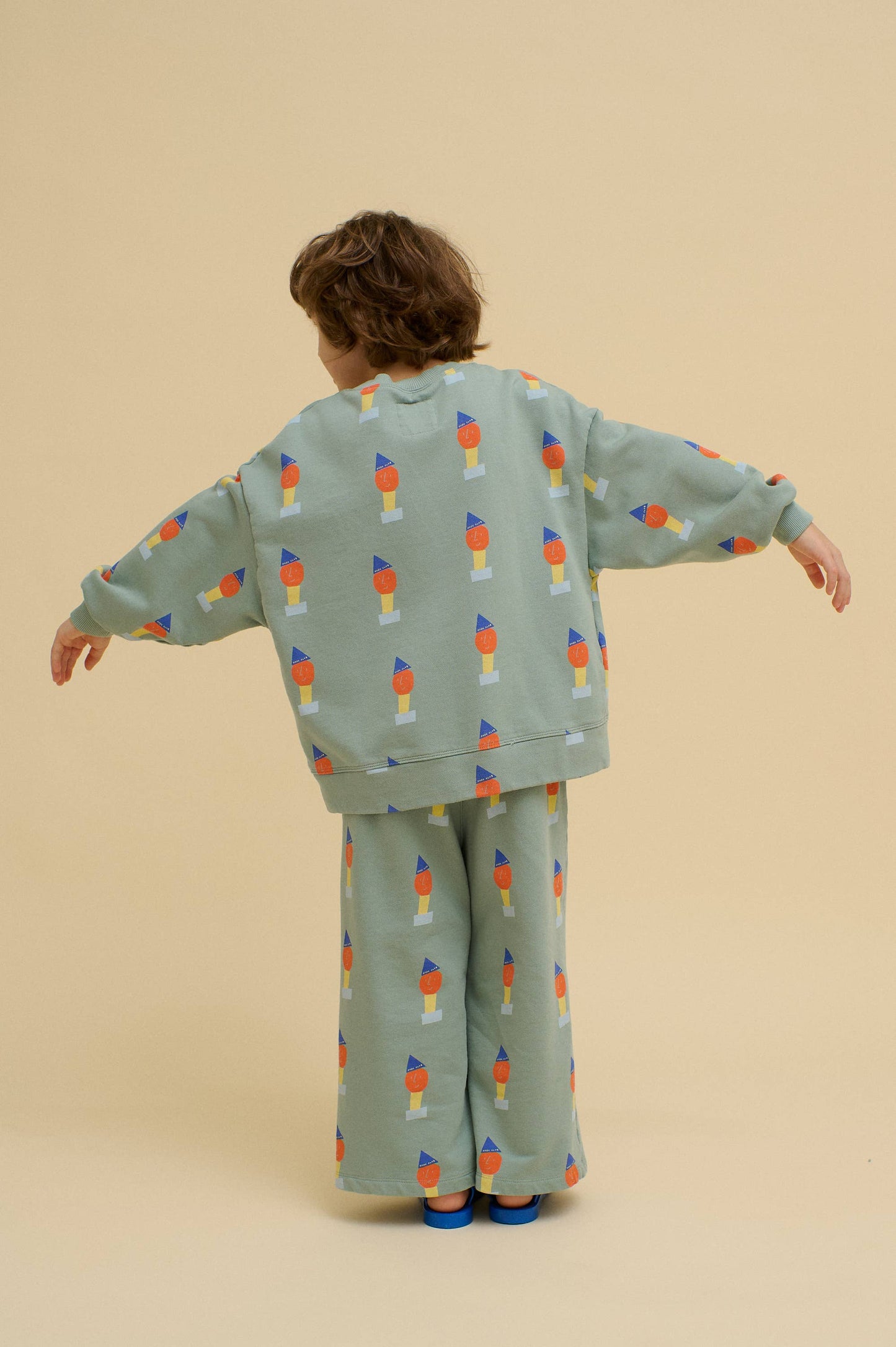 Child wearing a matching top and pants with colorful pattern on a beige background