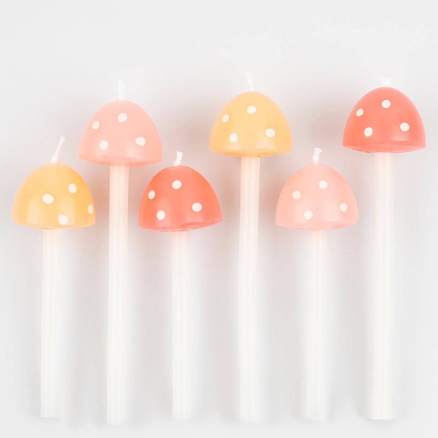 Set of mushroom-shaped candles with polka dot patterns on a white background