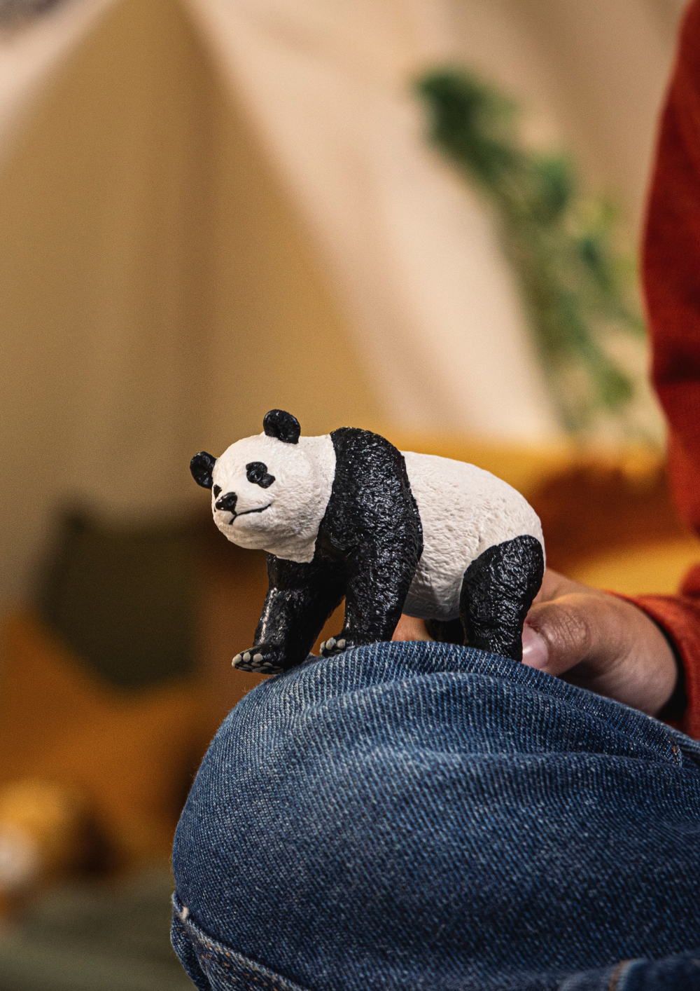 Panda figurine held in a person's hand with a blurred background