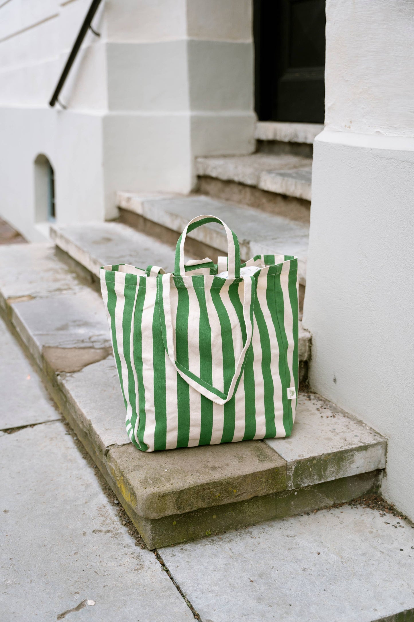 Green and white striped tote bag on stone steps