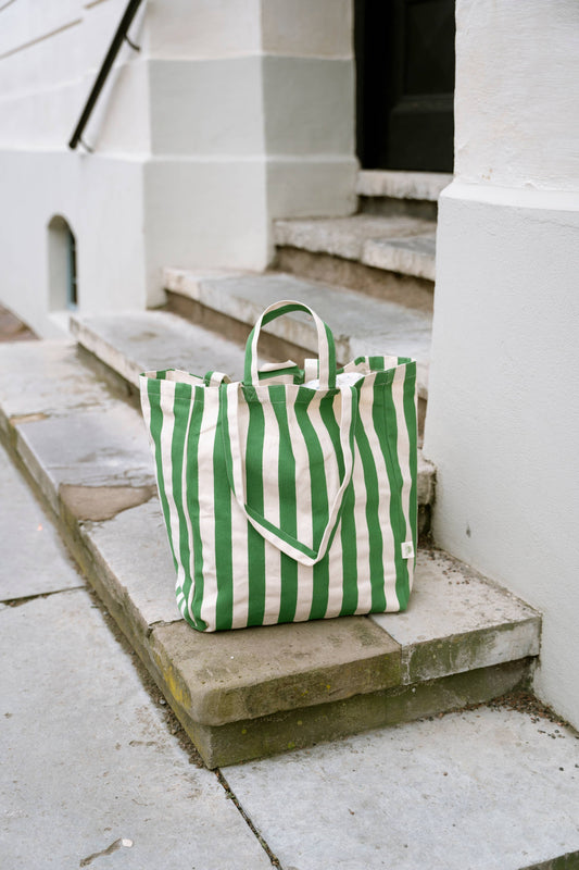 Green and white striped tote bag on stone steps