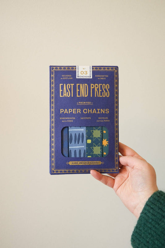 Hand holding the blue East End Press Blue & Yellow Paper Chain Kit box against a plain background.