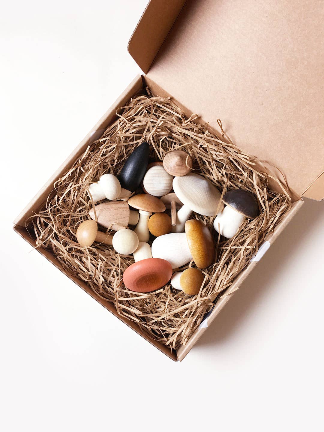 Box full of wooden mushrooms, with lid open, shown on a white background