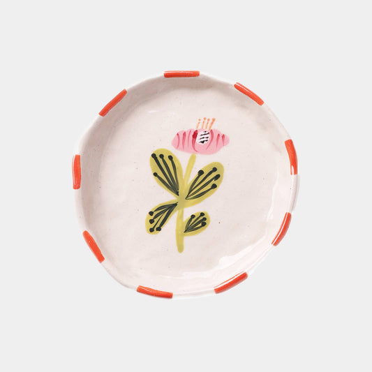 Small, round ceramic tray with hand-painted floral design on a white background