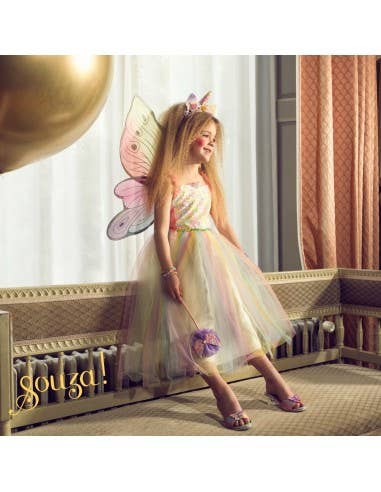 Child in a fairy costume with butterfly wings standing in a room with decorative elements.