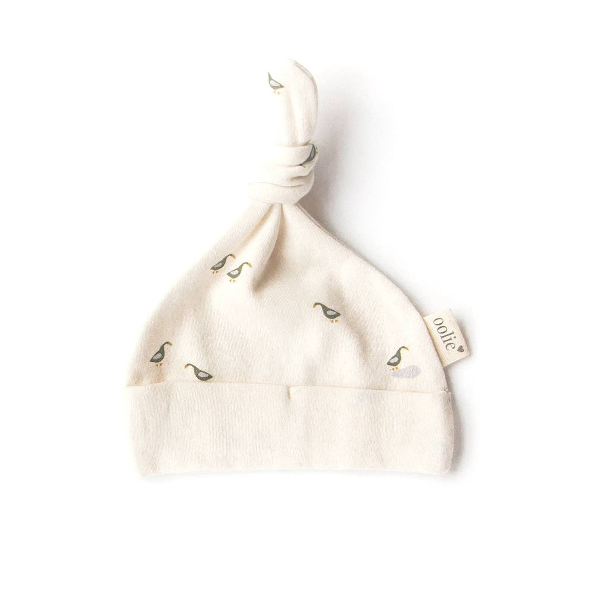 A cream-colored knit baby hat with a knot top, featuring small embroidered ducklings and a fabric tag that reads 'onite'.