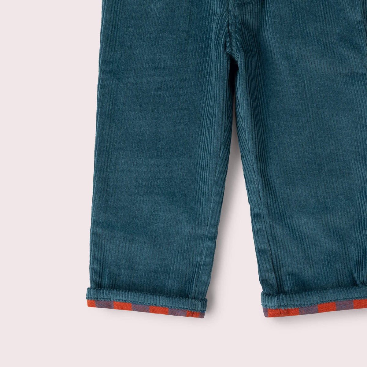 Close-up of teal corduroy trouser legs and turned-up cuffs with colorful check lining.