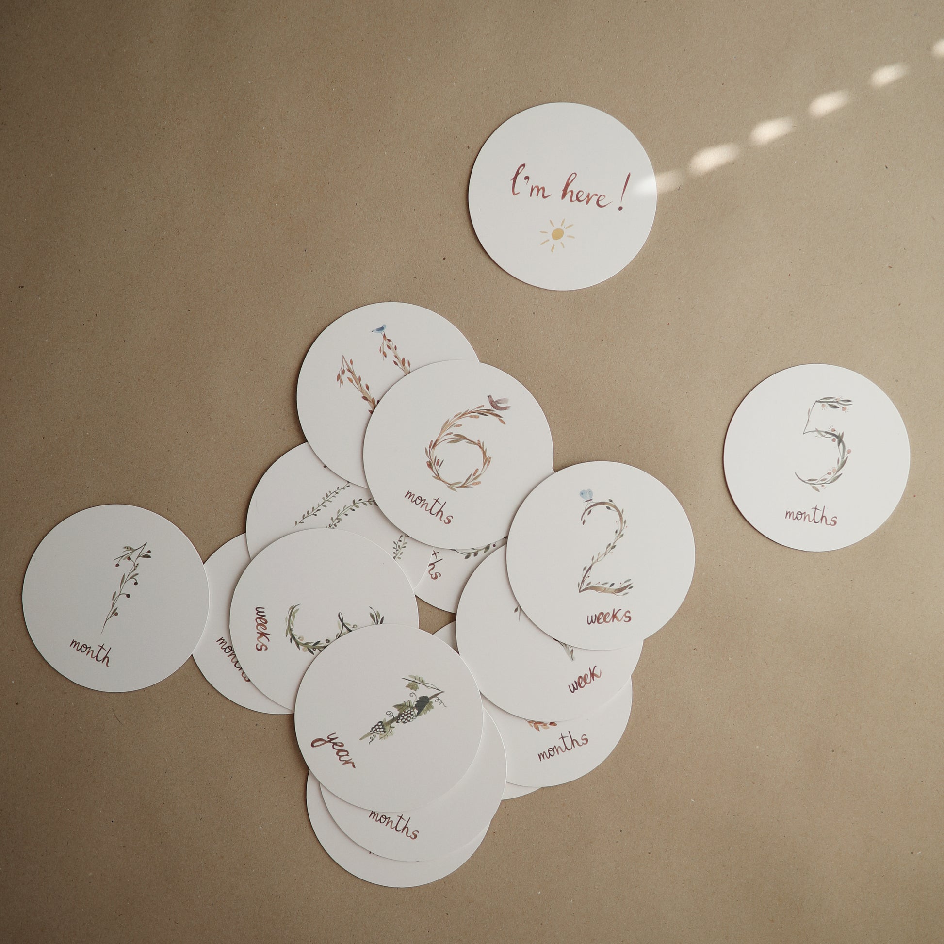 Round milestone cards on a brown surface with 'I'm here!' and numerical text.