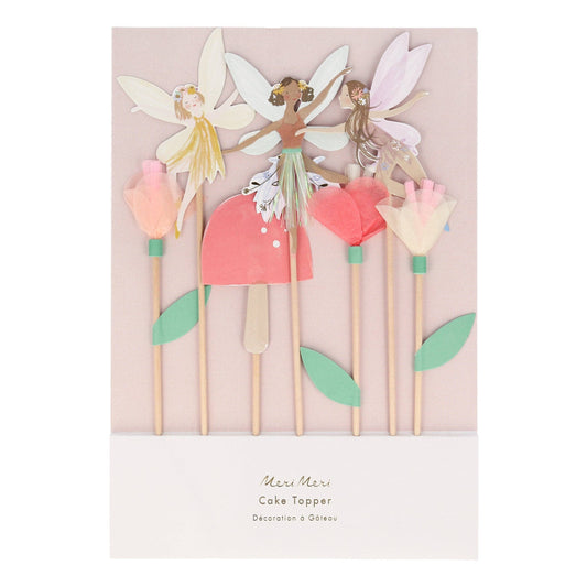 Set of fairy cake toppers with flowers on sticks against a light pink background