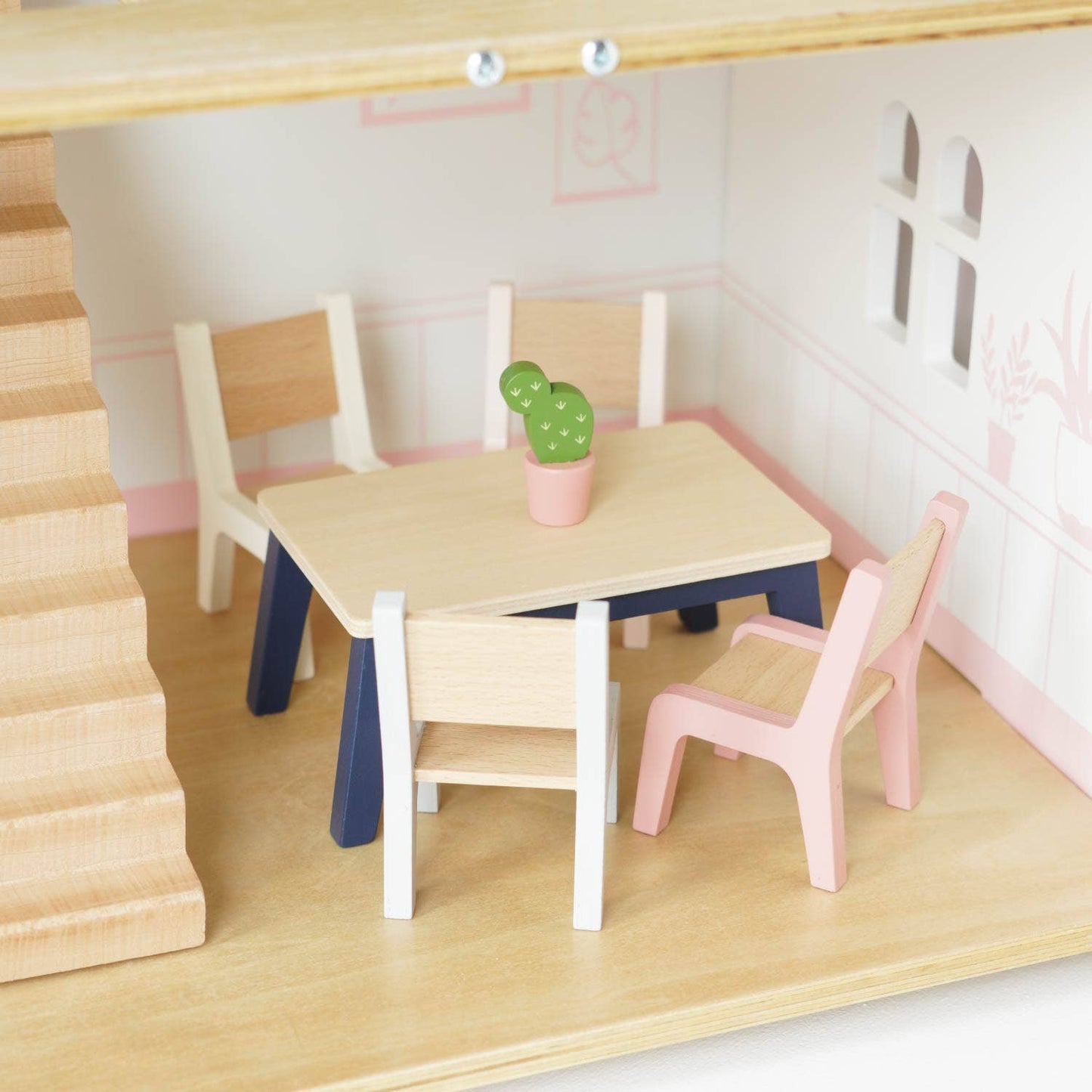 Set of wooden furniture including a table and chairs in a dollhouse setting.