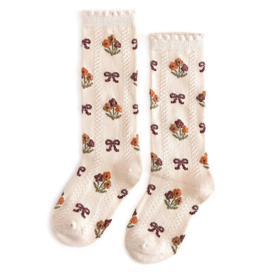 Pair of cream-colored socks with floral patterns on a white background