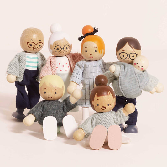 Set of wooden dolls representing an extended family on a light background