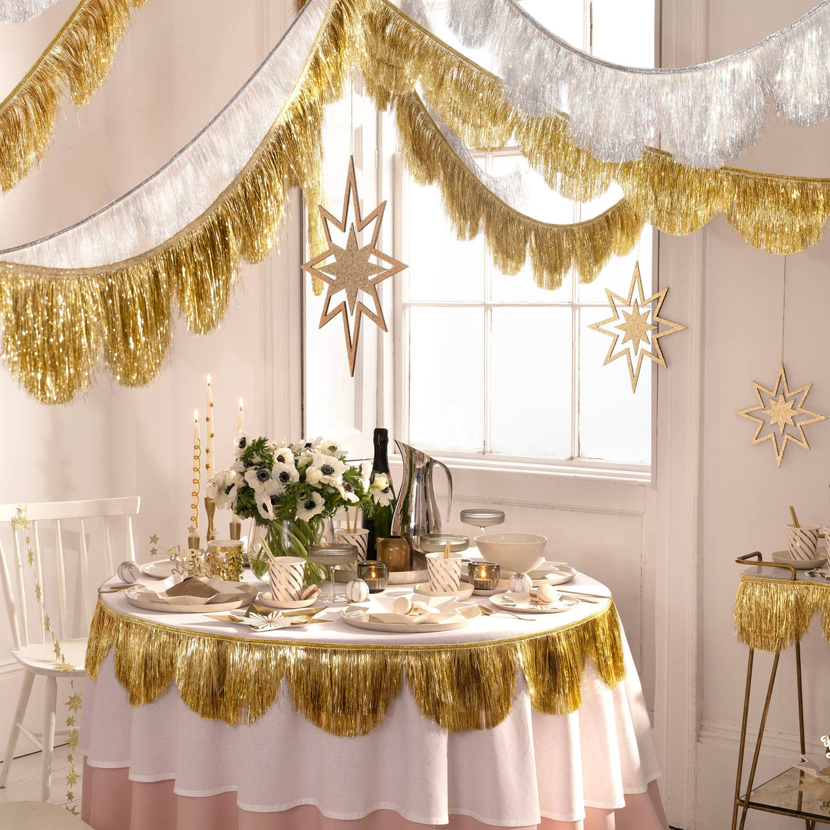 Decorated dining room with gold tinsel, white tablecloth, and festive decor.