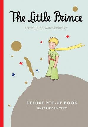 Cover of 'The Little Prince' deluxe pop-up book with a child standing on a rock, holding a yellow flower.