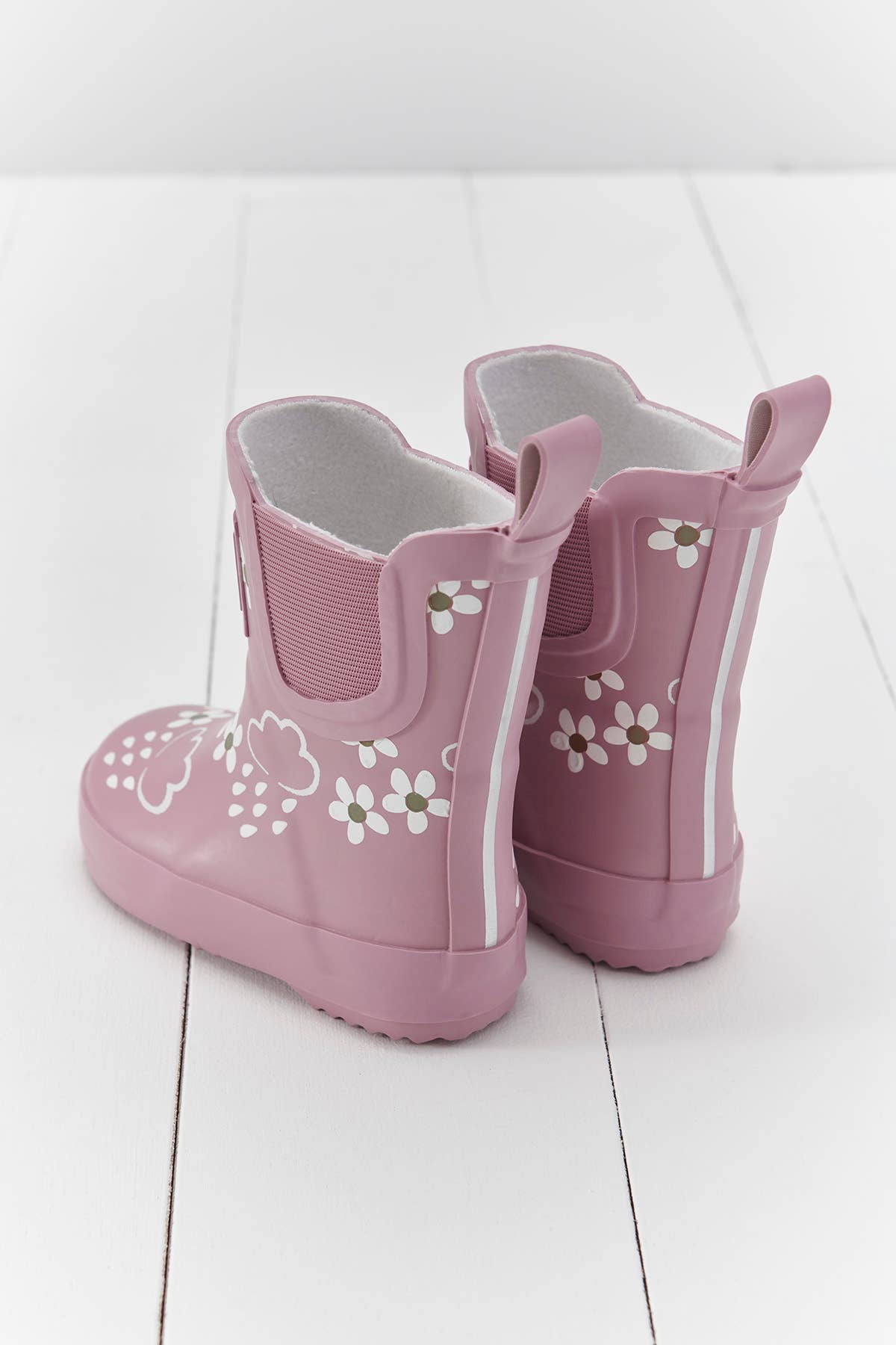 back view of pink rainboots on a white floor