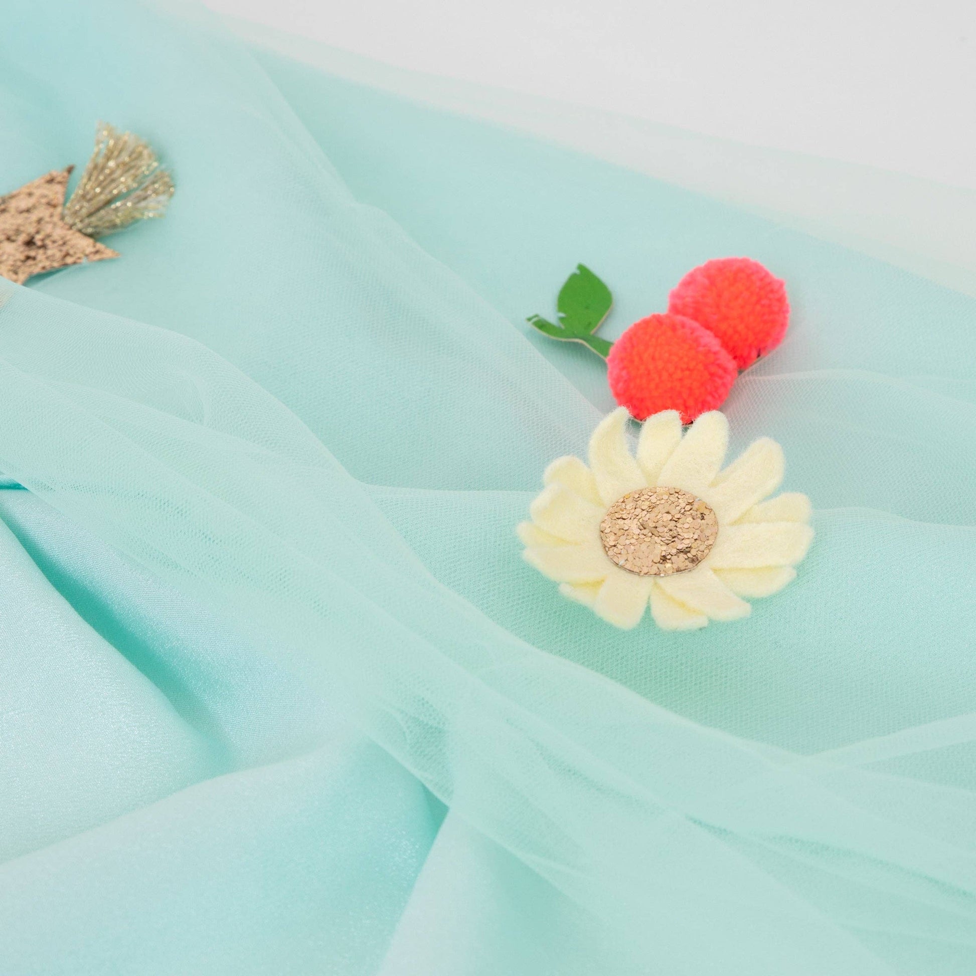 Close up of cherries and flower decoration on a light green/blue tulle fabric