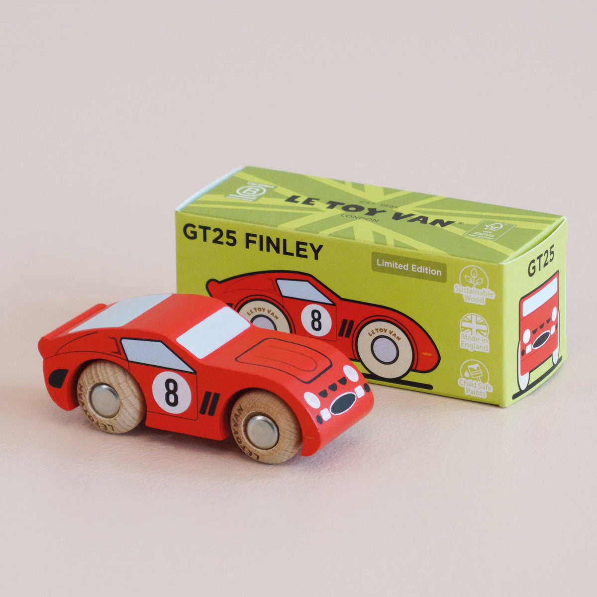 Red toy car with wooden wheels next to its packaging box on a beige background