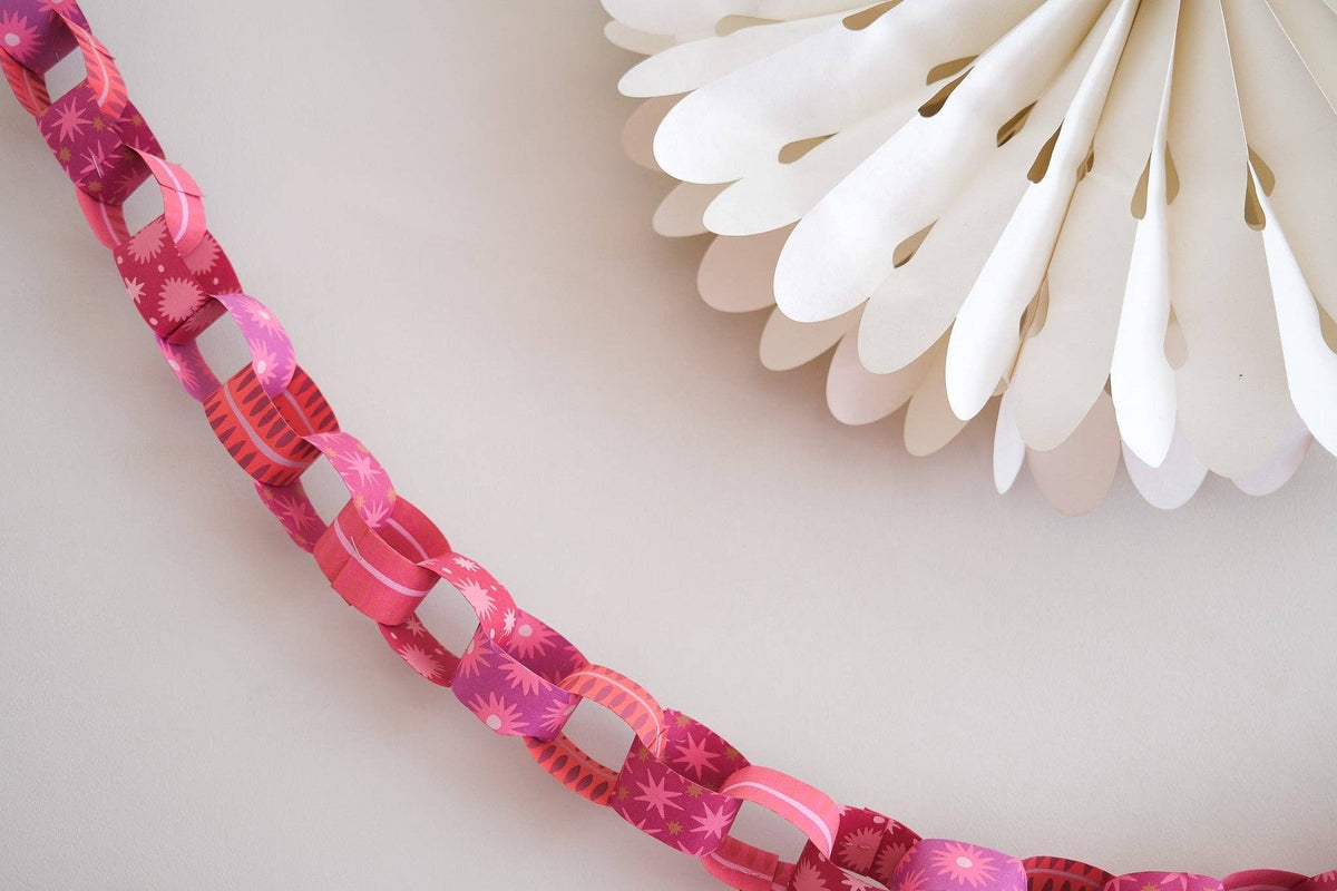 Pink and red patterned paper chain draped below a white paper rosette.