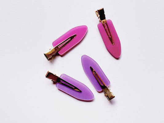 Three hair clips with pink and purple bases on a white background