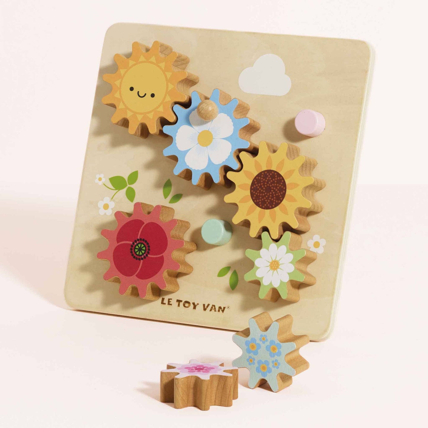 Wooden cog toy with colorful floral shapes on a light beige background