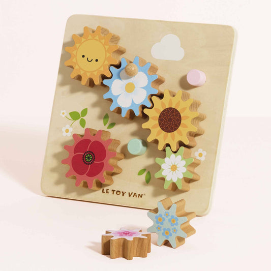 Wooden cog toy with colorful floral shapes on a light beige background