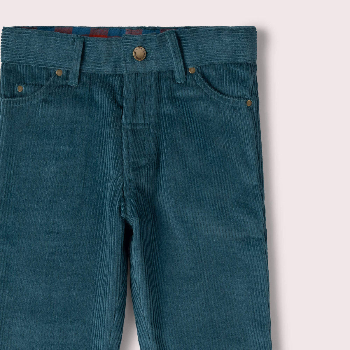 Detail of the button waistband, belt loops and front pockets on teal corduroy trousers.
