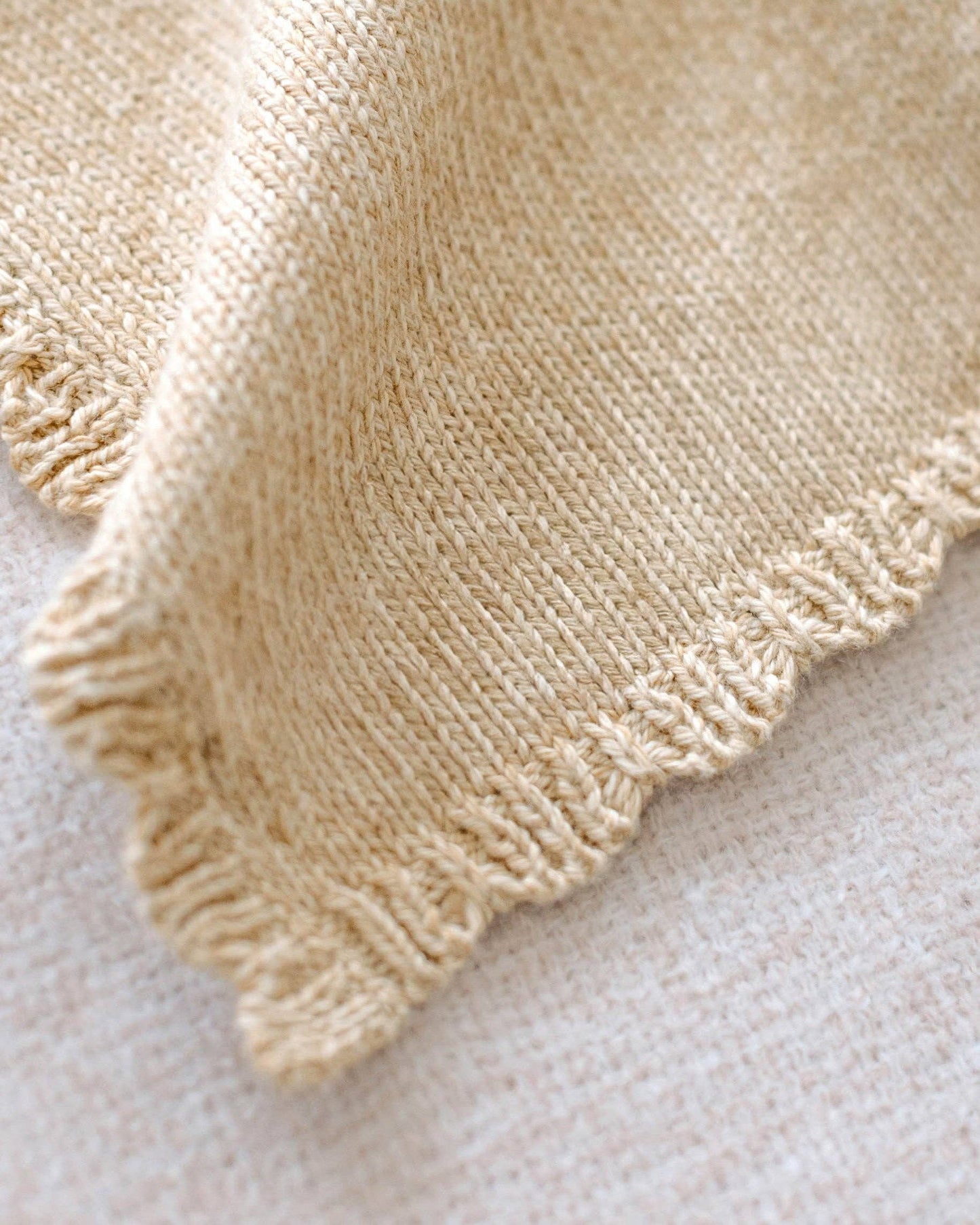 Close-up of a beige knitted baby lovey fabric on a light background