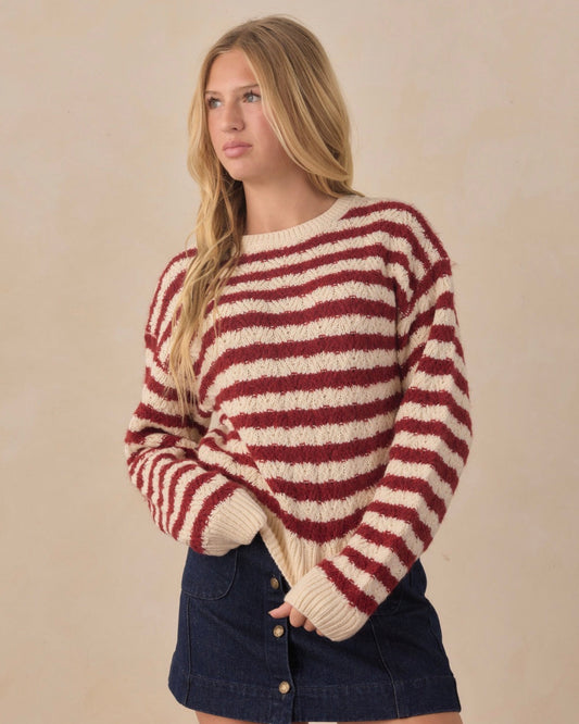 Teen wearing red and white striped long sleeve sweater and jean skirt in front of beige background