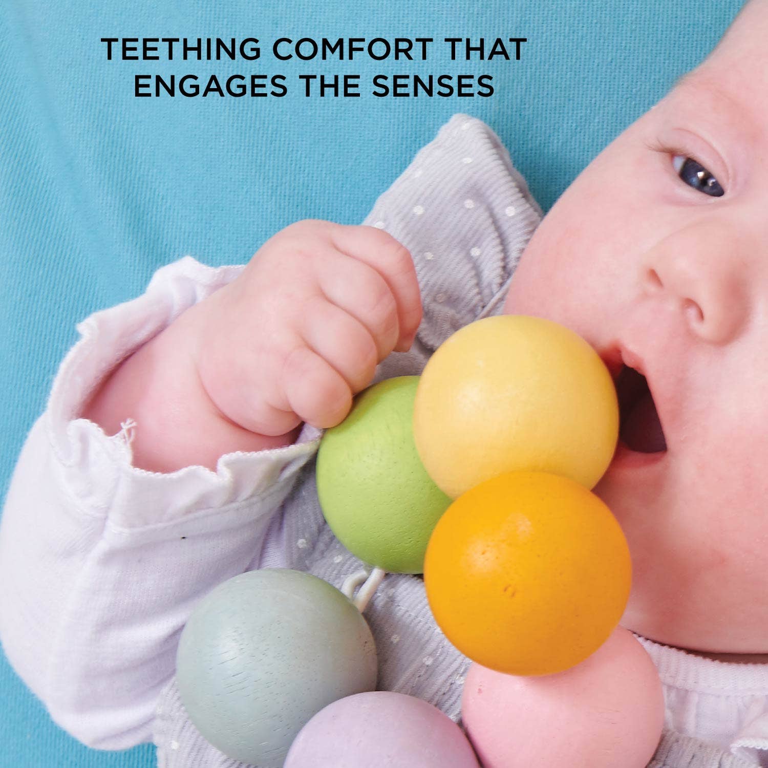 Baby playing with colorful teething balls against a blue background. "Teething comfort that engages the senses"