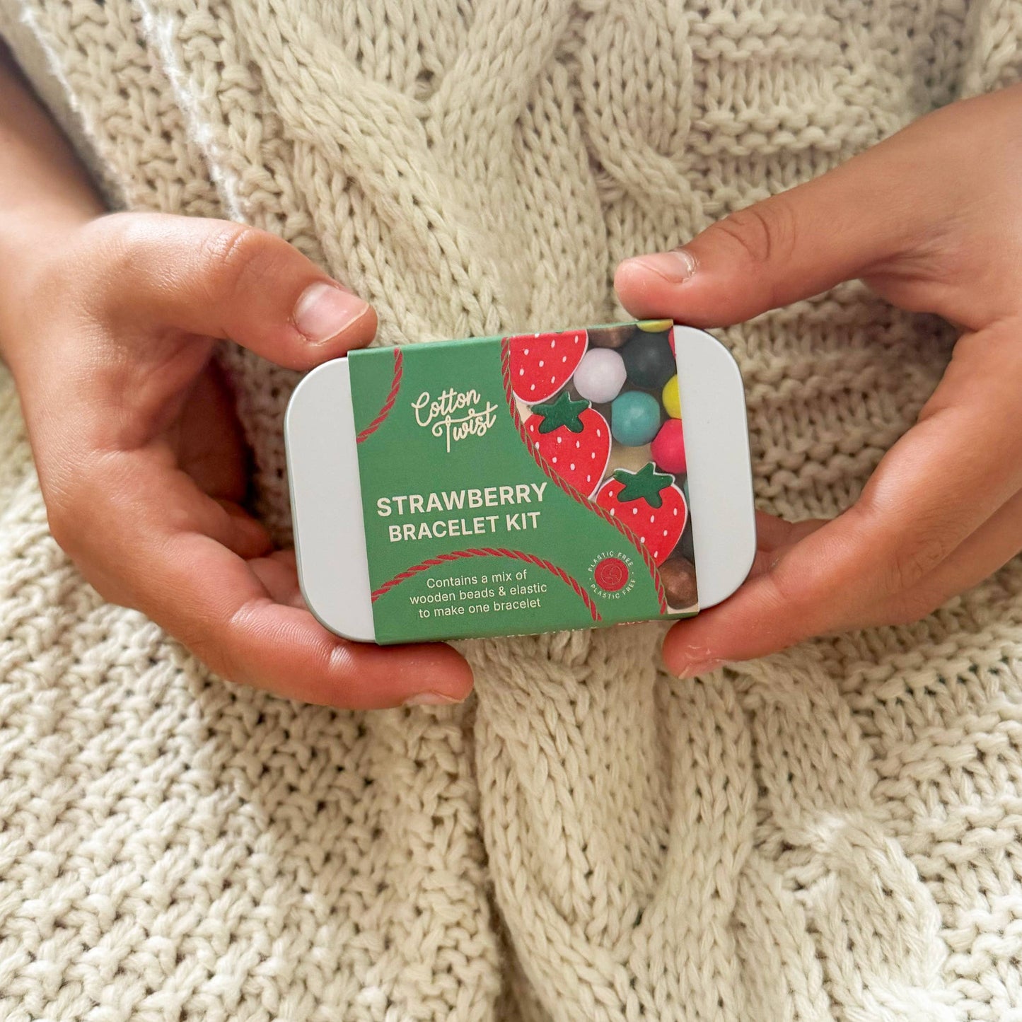 A child holding a strawberry bracelet kit