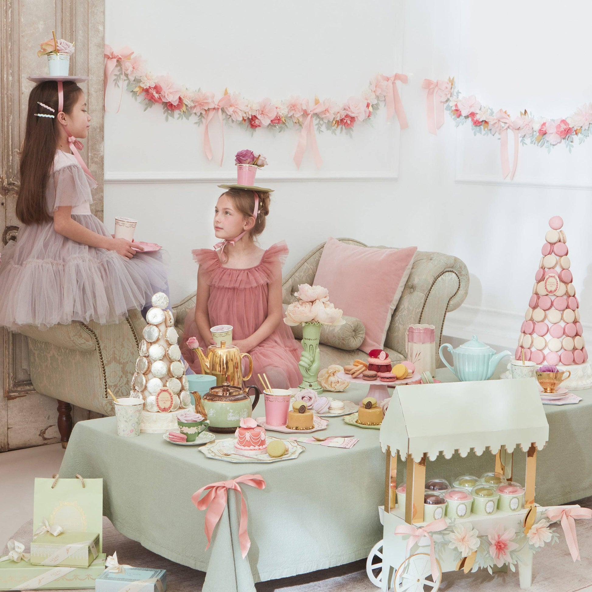 Two young girls at a tea party with decorative table setting and floral decorations.