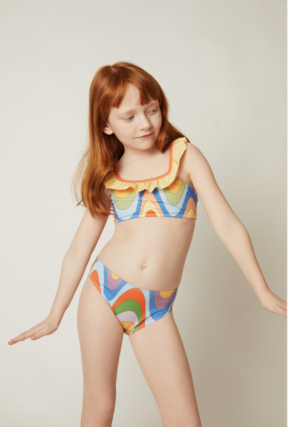 Young girl wearing a colorful bikini against a plain background