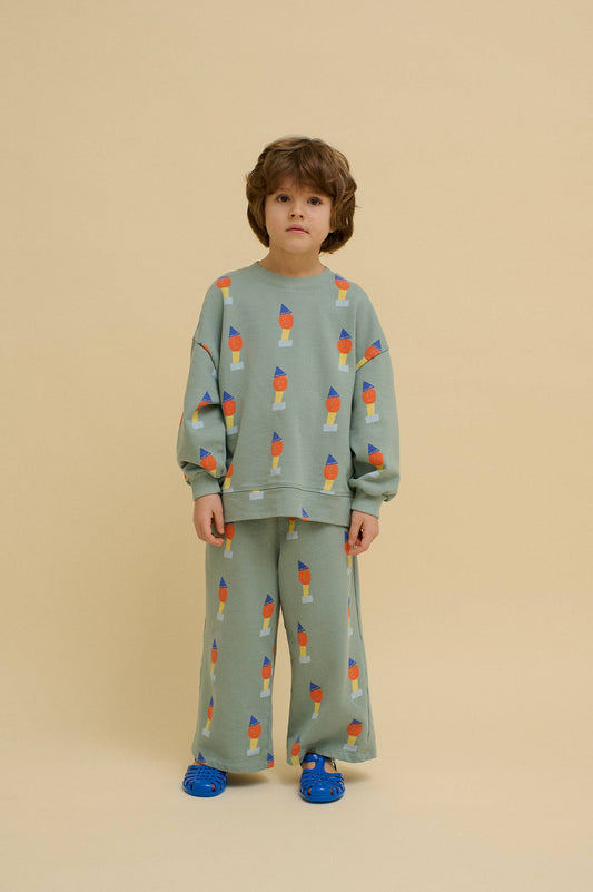 Child wearing a green outfit with colorful pattern on a beige background