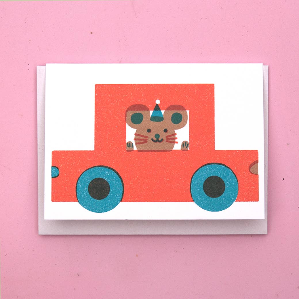 White Card with a cartoon mouse wearing a hat, in a red car on a pink background
