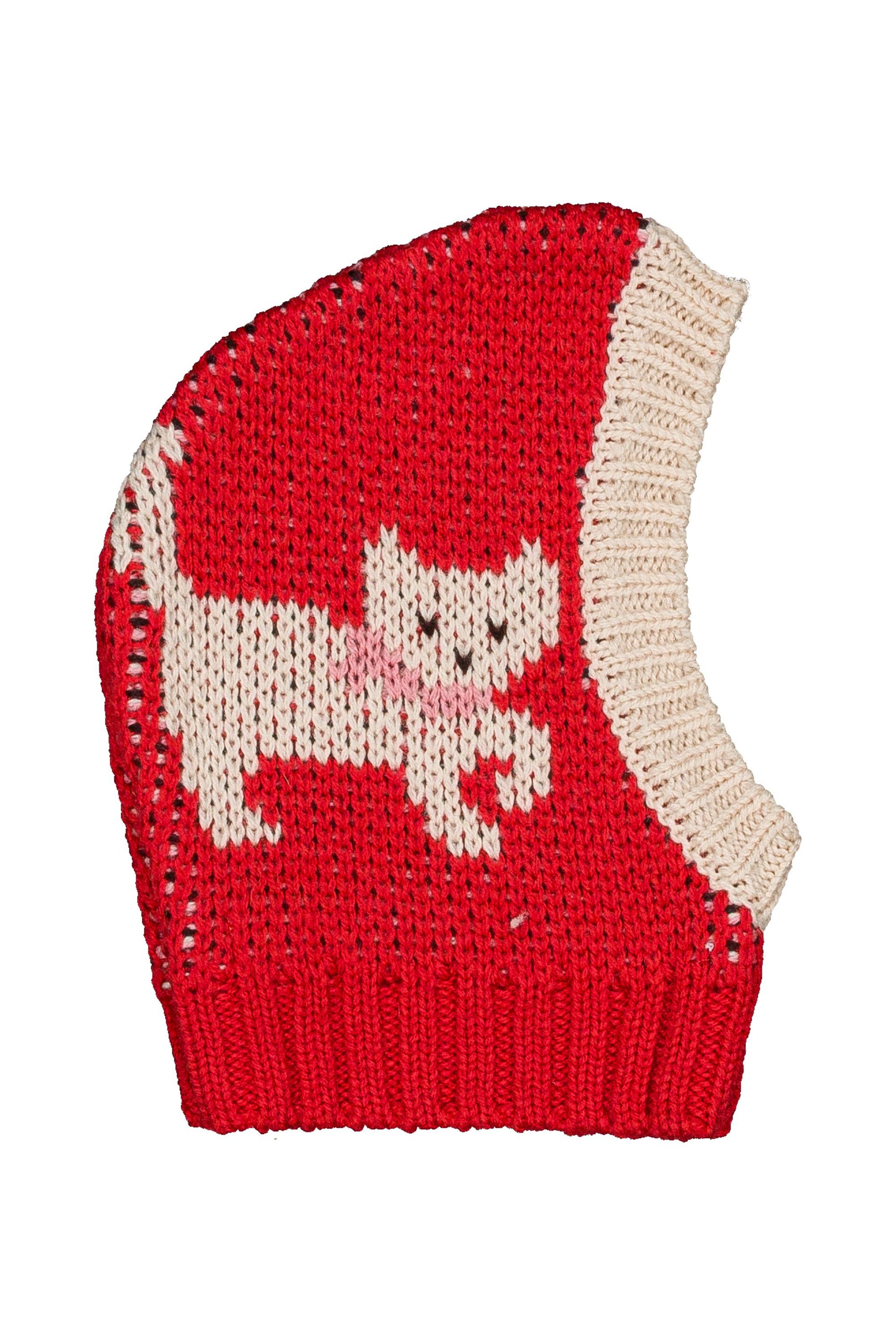 A red knit baby bonnet with a cream-colored cat motif and a cream ribbed trim, shown on a plain white background.