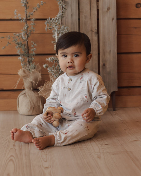 Baby wearing two piece casual set with a dalmation print, sitting in front of a wooden wall