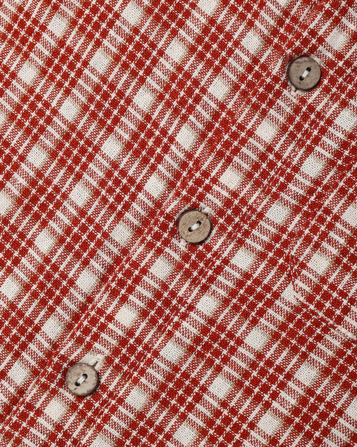 Close-up of a red and off-white plaid fabric with three visible brown buttons on a diagonal.