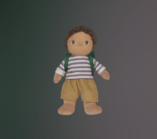 Toy doll figure of a child with green eyes and brown hair, wearing a striped purple and white shirt, brown corduroy shorts and green backpack on a dark background